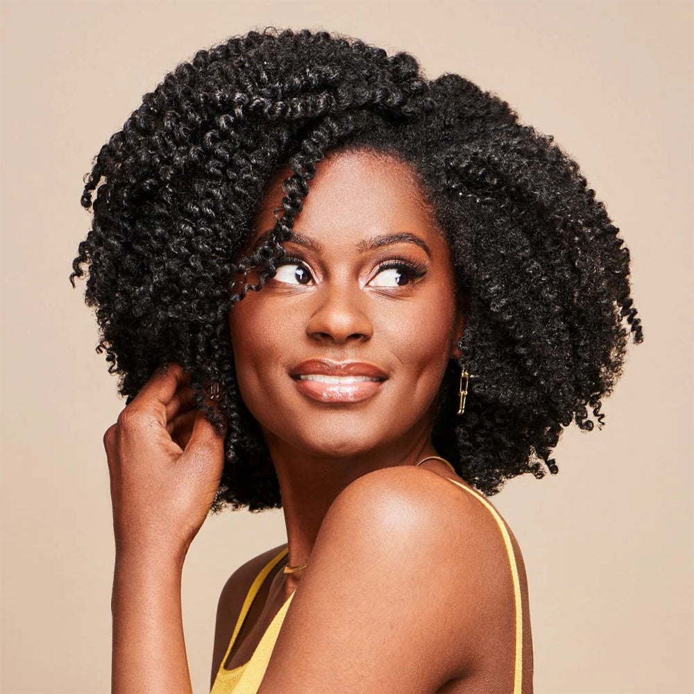 Kvinde med definerede, fugtede krøller og naturlig volumen, der illustrerer resultatet af African Pride Moisture Miracle Curling Cream.
