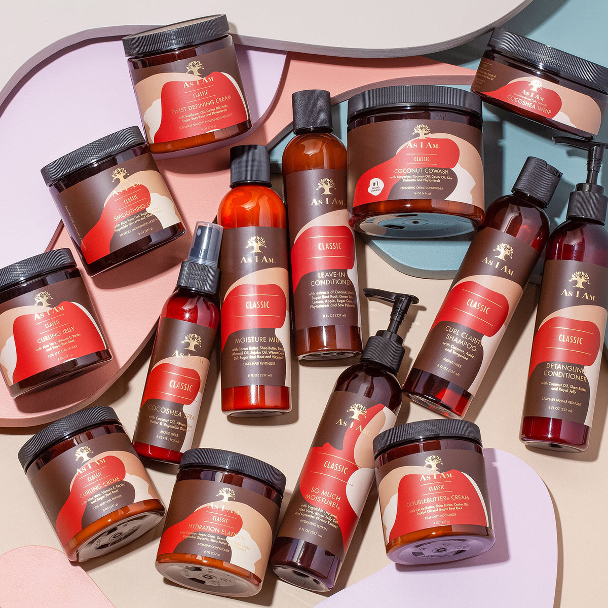 As I Am Classic hårplejeserie samlet i et flat lay med cremer, lotions, shampoo og leave-in produkter på farvet baggrund.