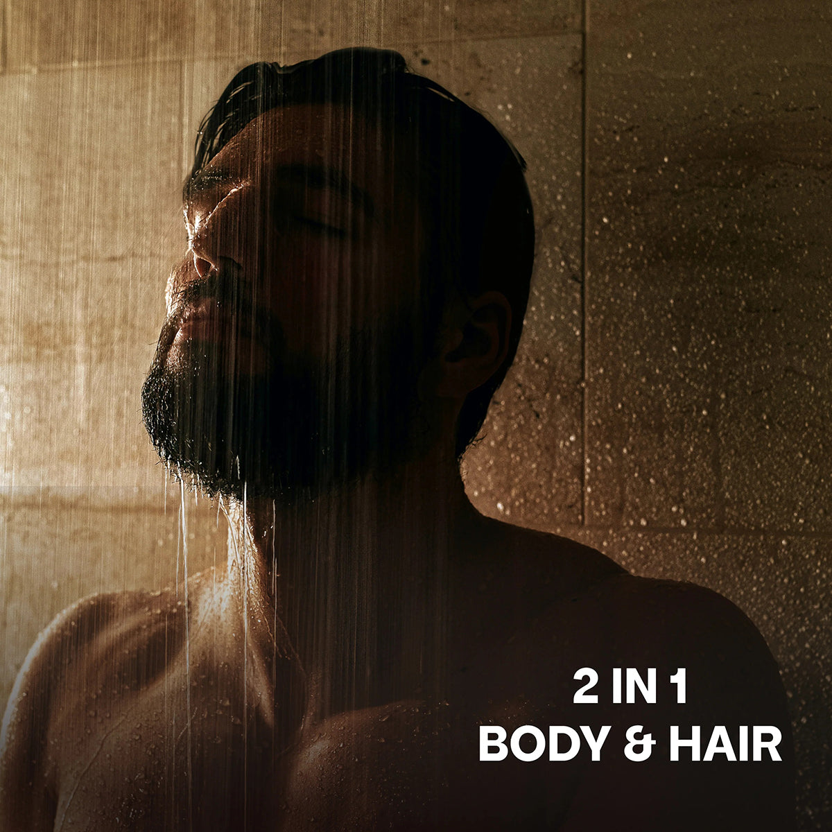 Mand under bruser i varmt lys med lukket øjne, anvender 2 in 1 Body & Hair shampoo til hår og krop.