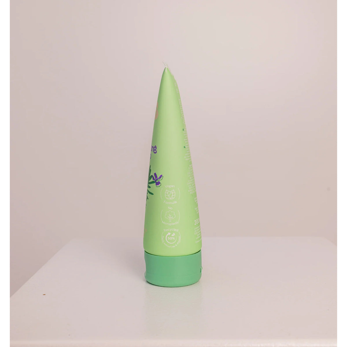 Grøn tube shampoo med grønt låg, veganskt og genbrugt plastik, står oprejst på hvid bordplade.