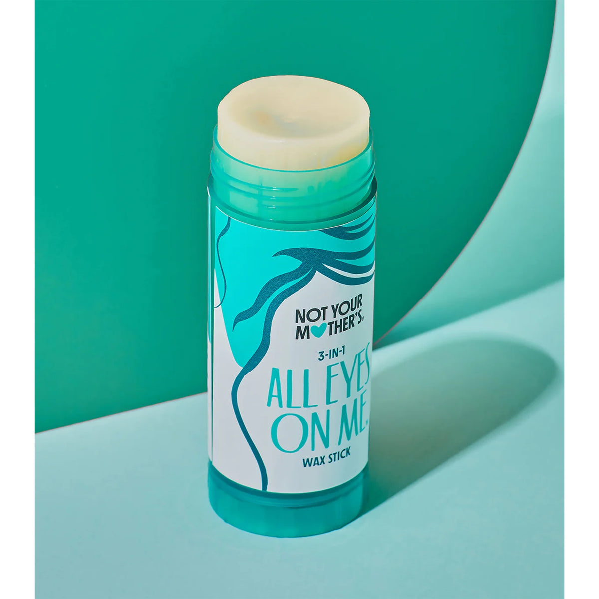 Not Your Mother's All Eyes On Me 3-in-1 wax stick i turkis tube på grøn baggrund.