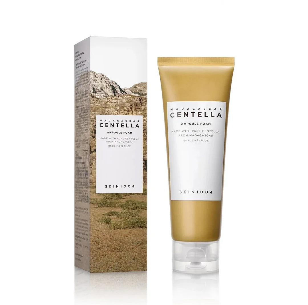 SKIN1004 Madagascar Centella Ampoule Foam 125ml i gylden tube ved siden af æske med naturmotiv i brune og grønne nuancer.