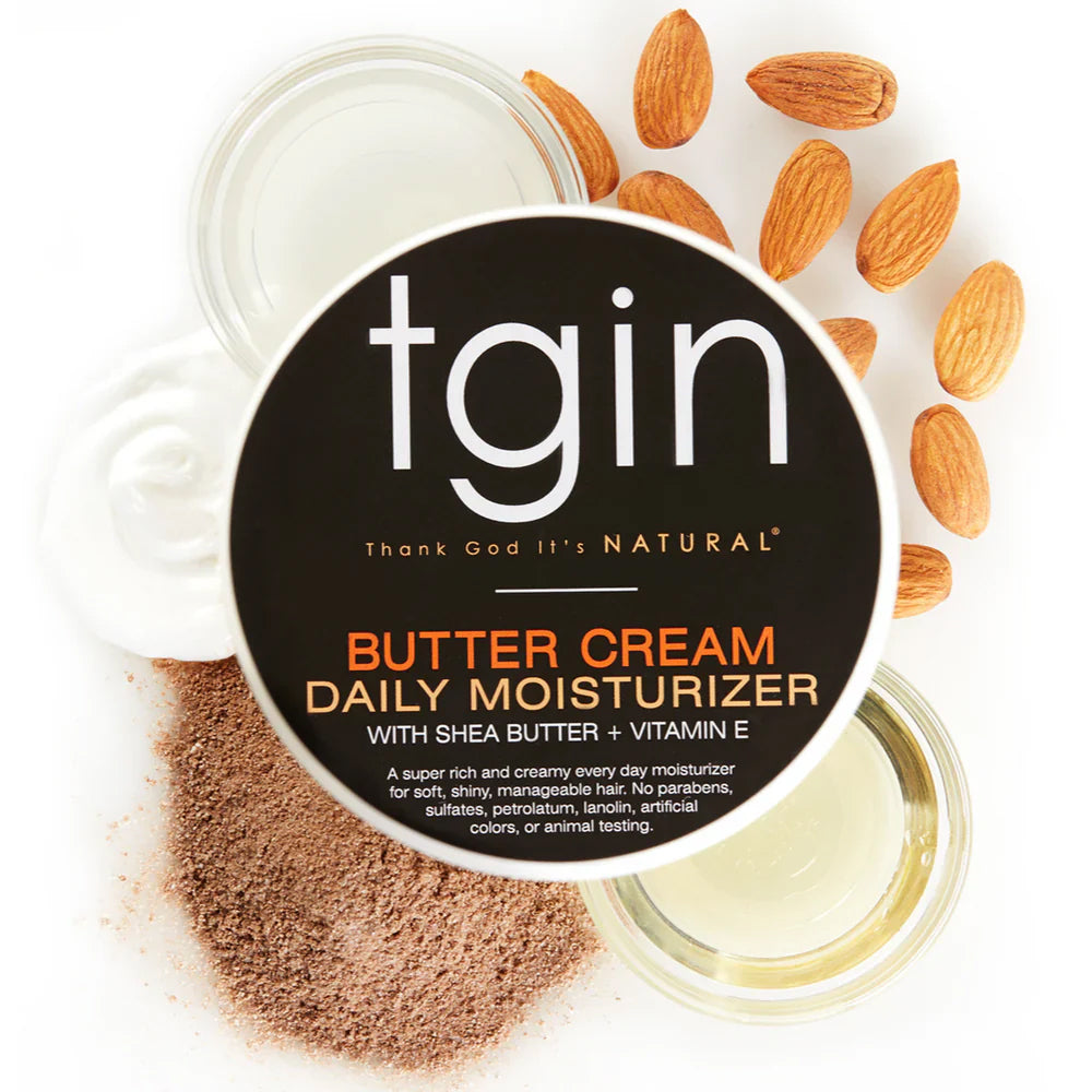 TGIN Butter Cream Daily Moisturizer 340gr med sheasmør og E-vitamin omgivet af mandler, olie og kakaopulver.